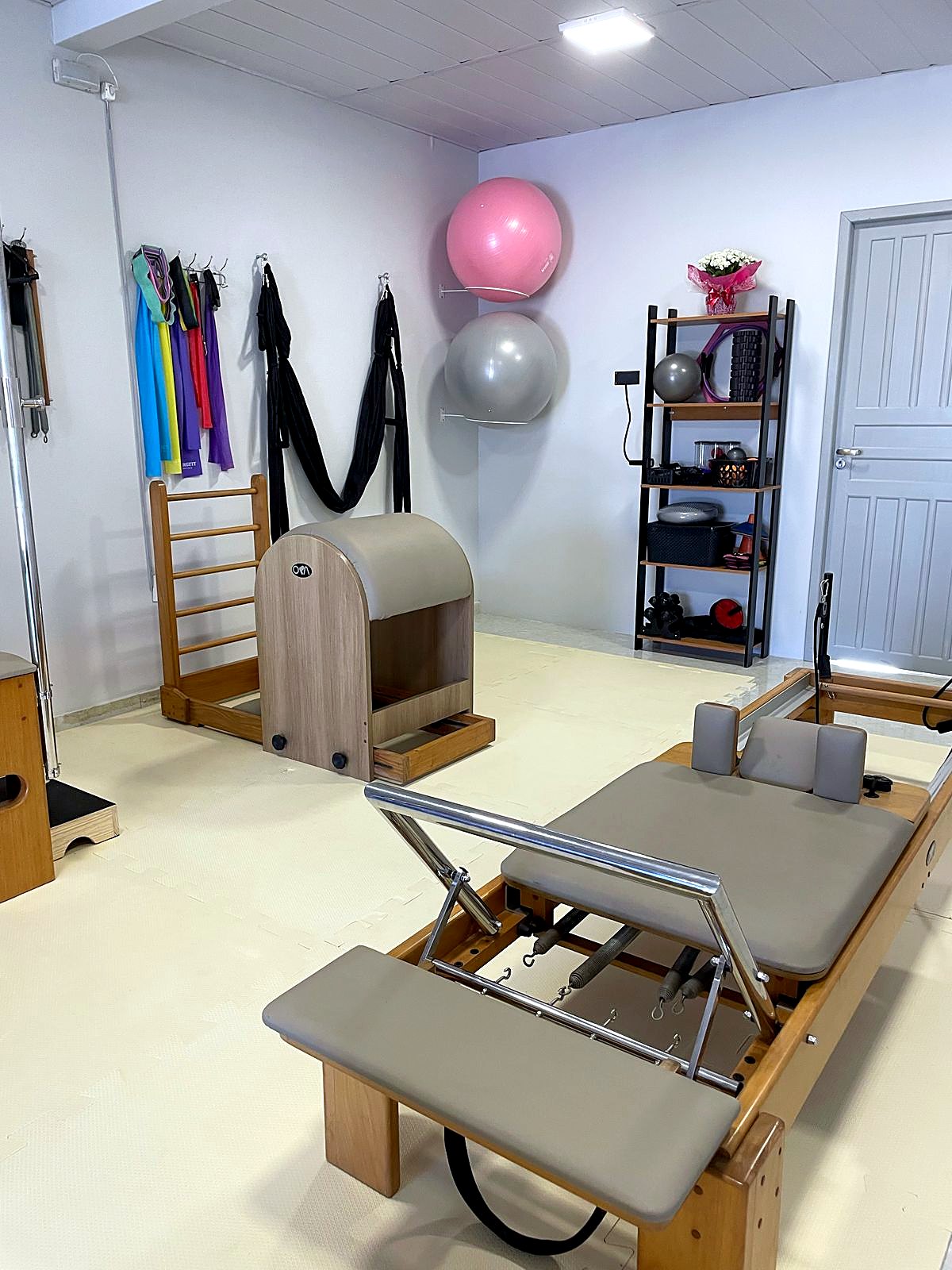 Reformer em primeiro plano e, ao fundo, Barrel, espaldar e acessórios de Pilates